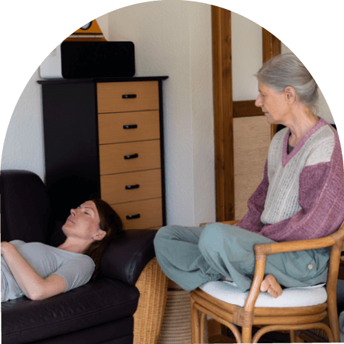 Das Bild zeigt Saskia John mit einer Klientin in entspannter liegender Position bei der Hypnosetherapie