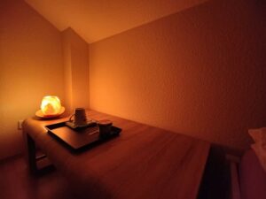 Das Bild zeigt einen Praxisraum für ein Dunkelretreat Ablauf mit etwas Atmosphäre durch einen beleuchteten Kristallstein und Tablet mit Getränk