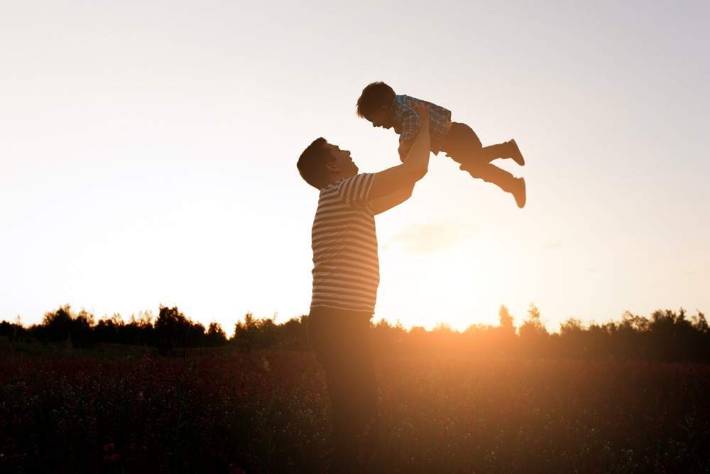 Vater und Sohn, die vor der untergehenden Sonne spielen Heilung des Inneren Kindes