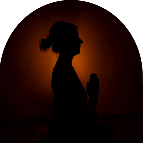 Saskia John im Dunkelretrat mit Händen in Gebetshaltung
