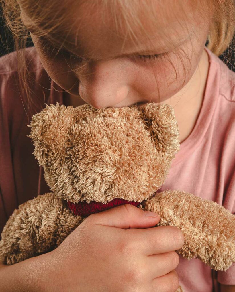 Das Bild zeigt ein Mädchen mit Teddybär im Arm und symbolisiert die Heilung des inneren Kindes